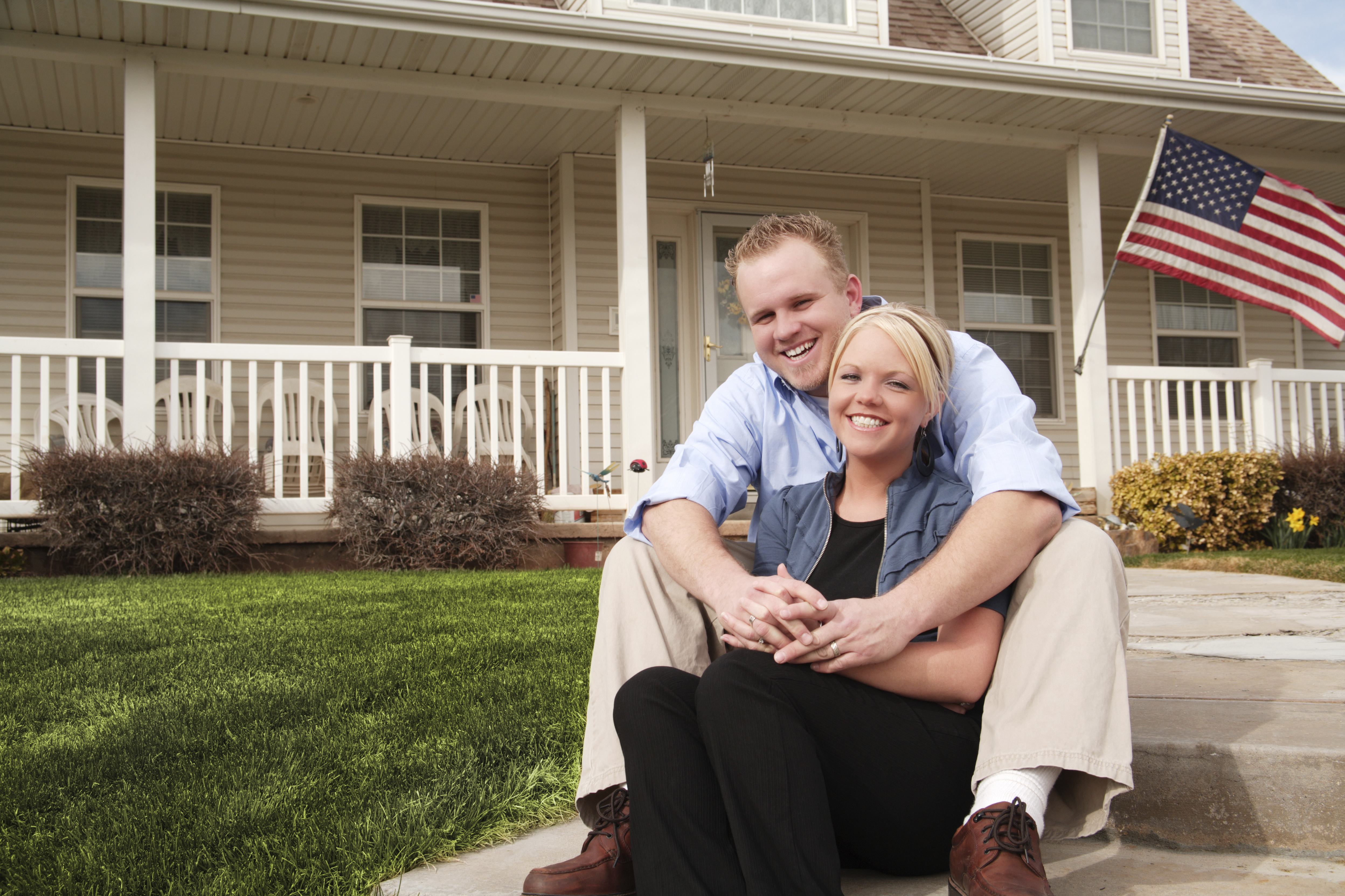 Happy couple smiling in front of there house